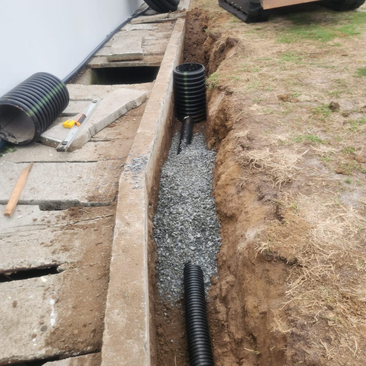 Subsurface drainage installation in progress with black piping laid at Darren Sammy Cricket Grounds by Turf Pro Landscaping.